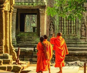 Three monks walking through the Buddhist temple of Ta Prohm, Angkor Wat